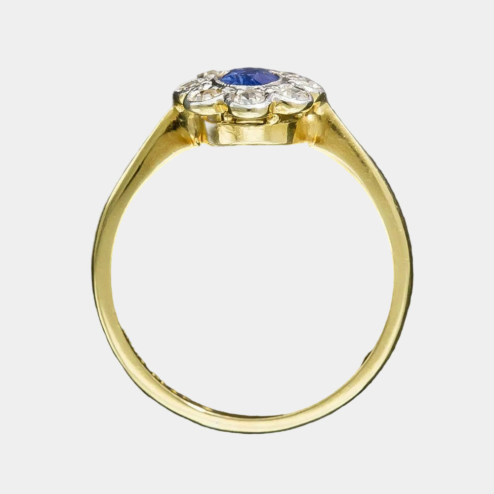 Gold ring with a blue gemstone and diamond accents on a dark background