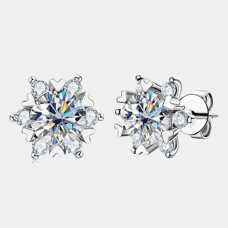 Pair of silver snowflake-shaped earrings with clear gemstones on a light gray background