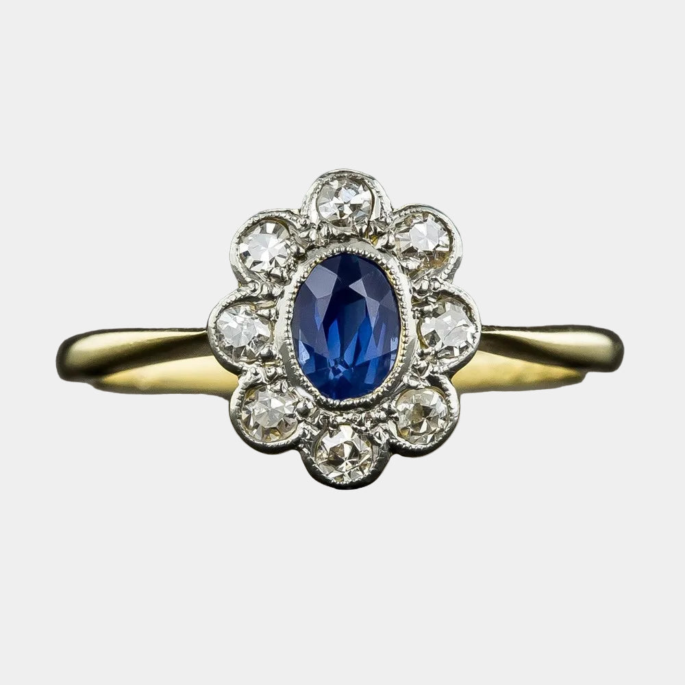 Gold ring with a blue gemstone and diamond accents on a dark background