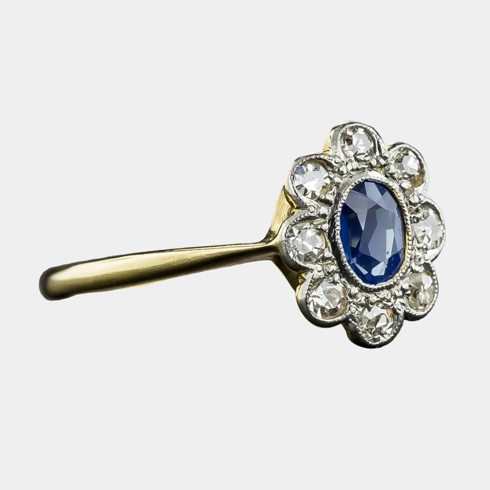 Gold ring with a blue gemstone and diamond accents on a dark background