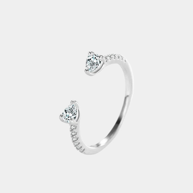 Silver open bangle with heart-shaped gemstones on a light gray background